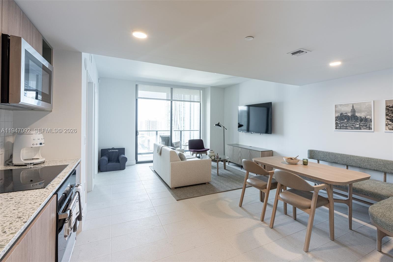 A modern open-concept living and dining area features a kitchen, balcony, and neutral furniture — 601 NE 1st ave # 3109, Miami FL 33132, MIAMI, FL