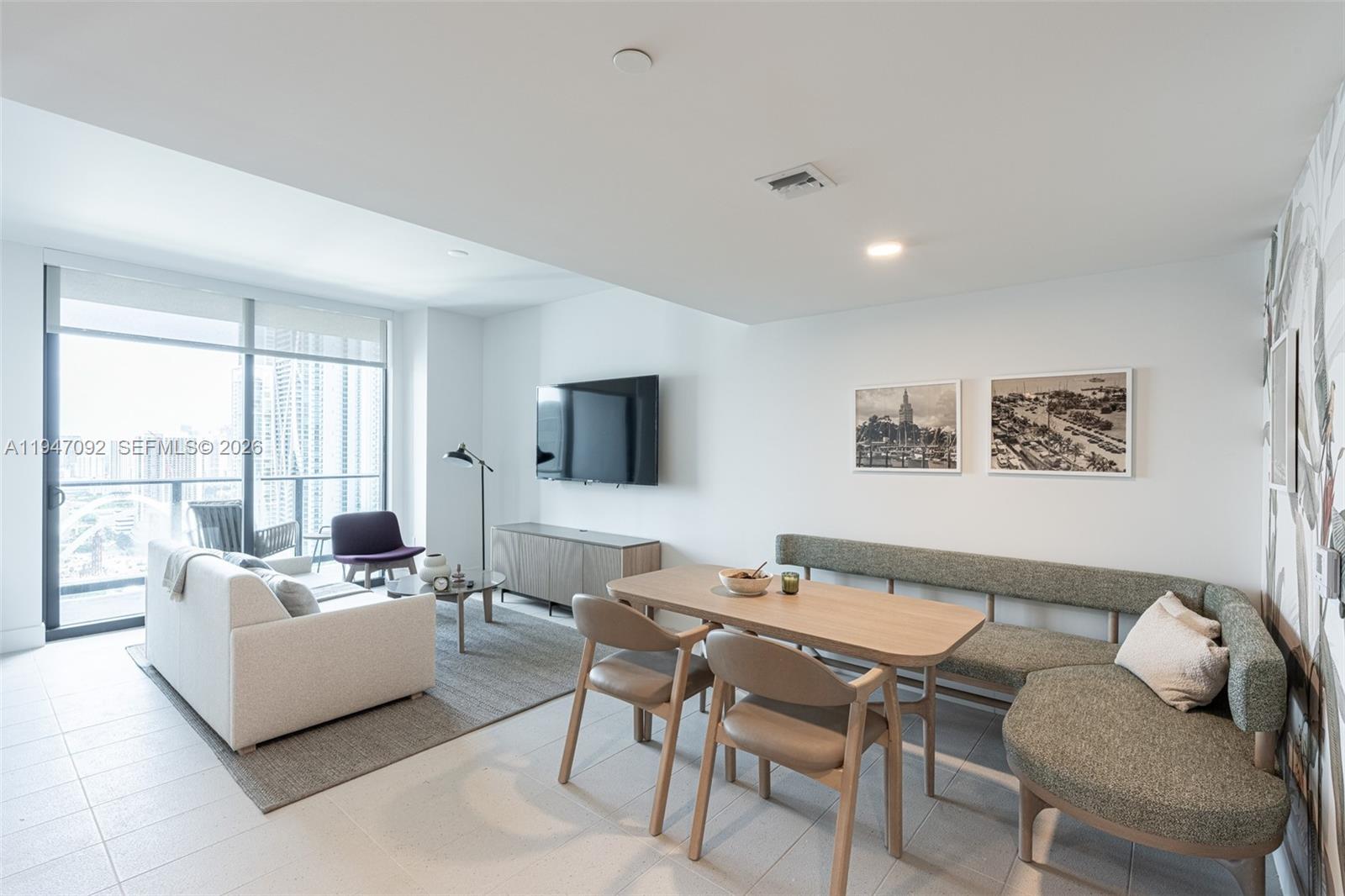 A living and dining area features a sofa, television, and a banquette dining set — 601 NE 1st ave # 3109, Miami FL 33132, MIAMI, FL