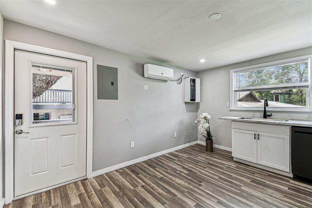 A room with wood-look flooring, a white door, a sink, and a wall-mounted air conditioner — 1006 E 26TH AVENUE UNIT 1, TAMPA, FL