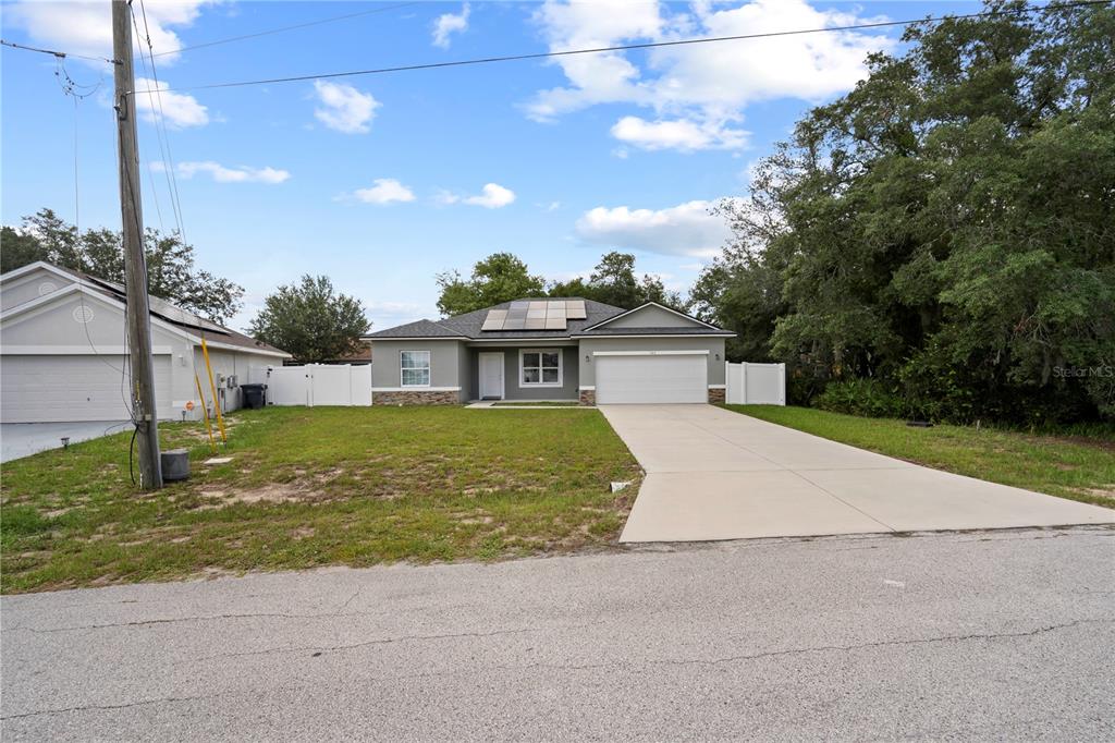 A single-story house with a gray exterior, a two-car garage, and rooftop solar panels — 464 DANUBE DRIVE, POINCIANA, FL