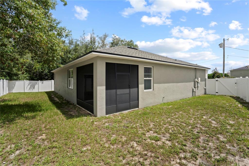 The exterior of a house features a screened-in porch and a white vinyl fence — 464 DANUBE DRIVE, POINCIANA, FL