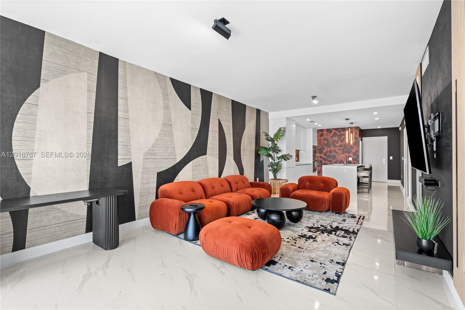 A modern living room features a large orange sofa, patterned wallpaper, and white tile floors — 700 NE 24th St # 5206, Miami FL 33137, MIAMI, FL