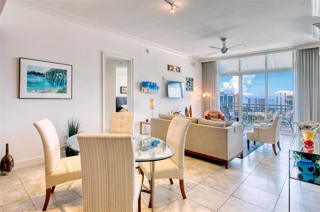 A dining area and living room with tile floors, glass table, and balcony ocean view — 1350 MAIN STREET UNIT 1702, SARASOTA, FL