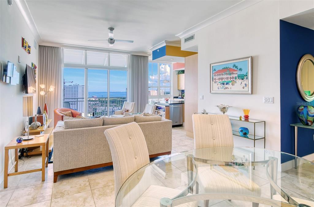 A bright living and dining area features tile floors, a glass table, and balcony ocean views — 1350 MAIN STREET UNIT 1702, SARASOTA, FL