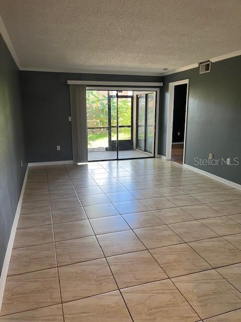An empty living room features light-colored tile flooring, dark gray walls, and a sliding glass door — 10199 SAILWINDS BOULEVARD S UNIT 102, LARGO, FL