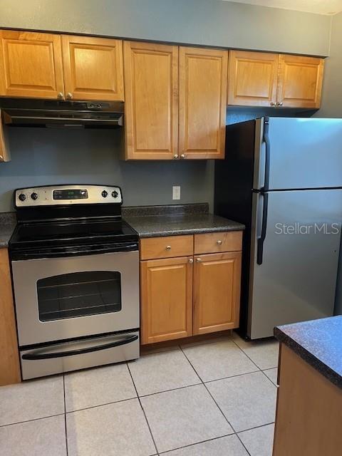A kitchen features light wood cabinets, stainless steel appliances, and tile flooring — 10199 SAILWINDS BOULEVARD S UNIT 102, LARGO, FL