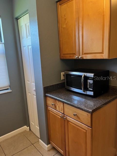 A kitchen area features wooden cabinets, a countertop, and a microwave next to a door — 10199 SAILWINDS BOULEVARD S UNIT 102, LARGO, FL