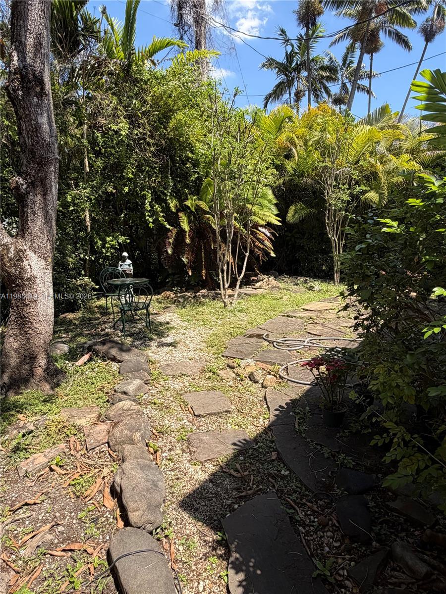 A backyard garden features a stone path, gravel ground, and a small metal bistro set — 1209 Mariana Ave, Coral Gables FL 33134, CORAL GABLES, FL