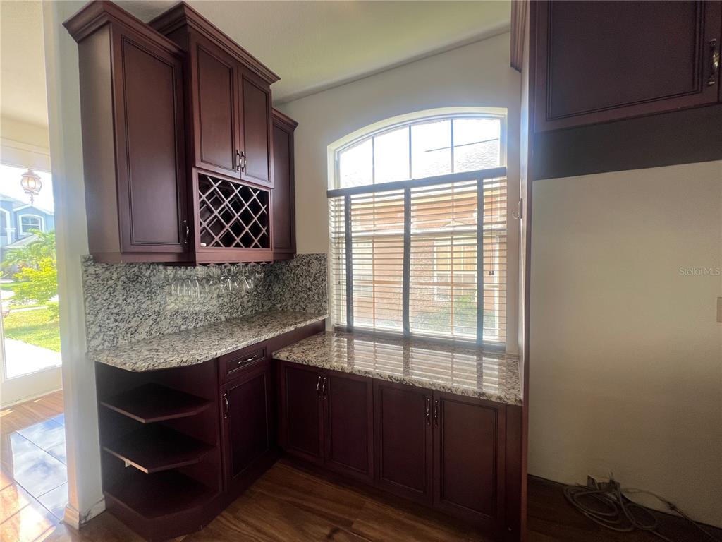 A kitchen bar area features dark wood cabinetry, granite countertops, and a built-in wine rack — 6222 LAUREL CREEK TRAIL, ELLENTON, FL