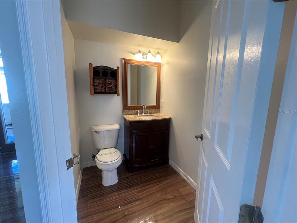 A small bathroom features a wood vanity, a toilet, and a wall-mounted storage cabinet — 6222 LAUREL CREEK TRAIL, ELLENTON, FL
