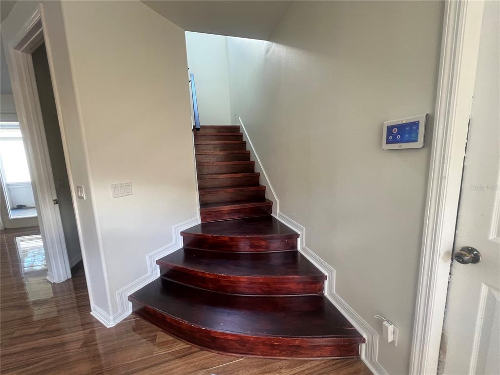 A wooden staircase with curved bottom steps leads upward in a hallway with light walls — 6222 LAUREL CREEK TRAIL, ELLENTON, FL