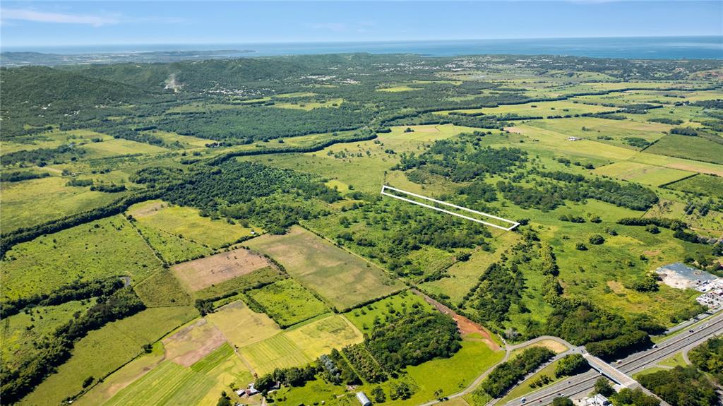 An aerial view shows a large, grassy plot of land outlined in white near a highway — 2 KM 162 BENAVENTE ROAD UNIT 726, HORMIGUEROS, PR