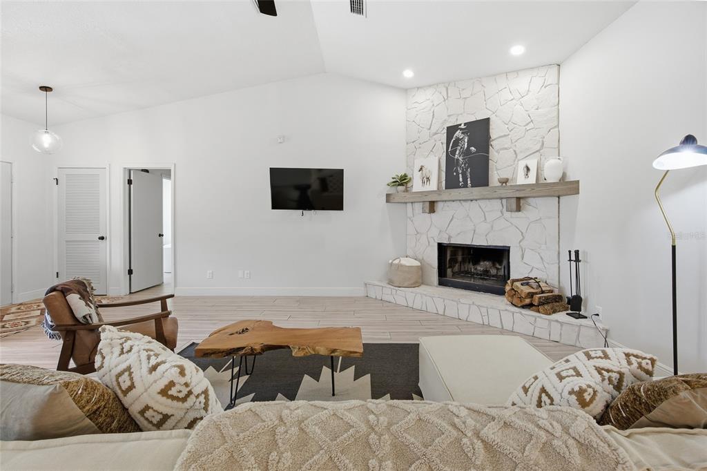 A living room features a white stone corner fireplace, a wood mantel, and tile flooring — 8274 NW 47TH STREET, OCALA, FL