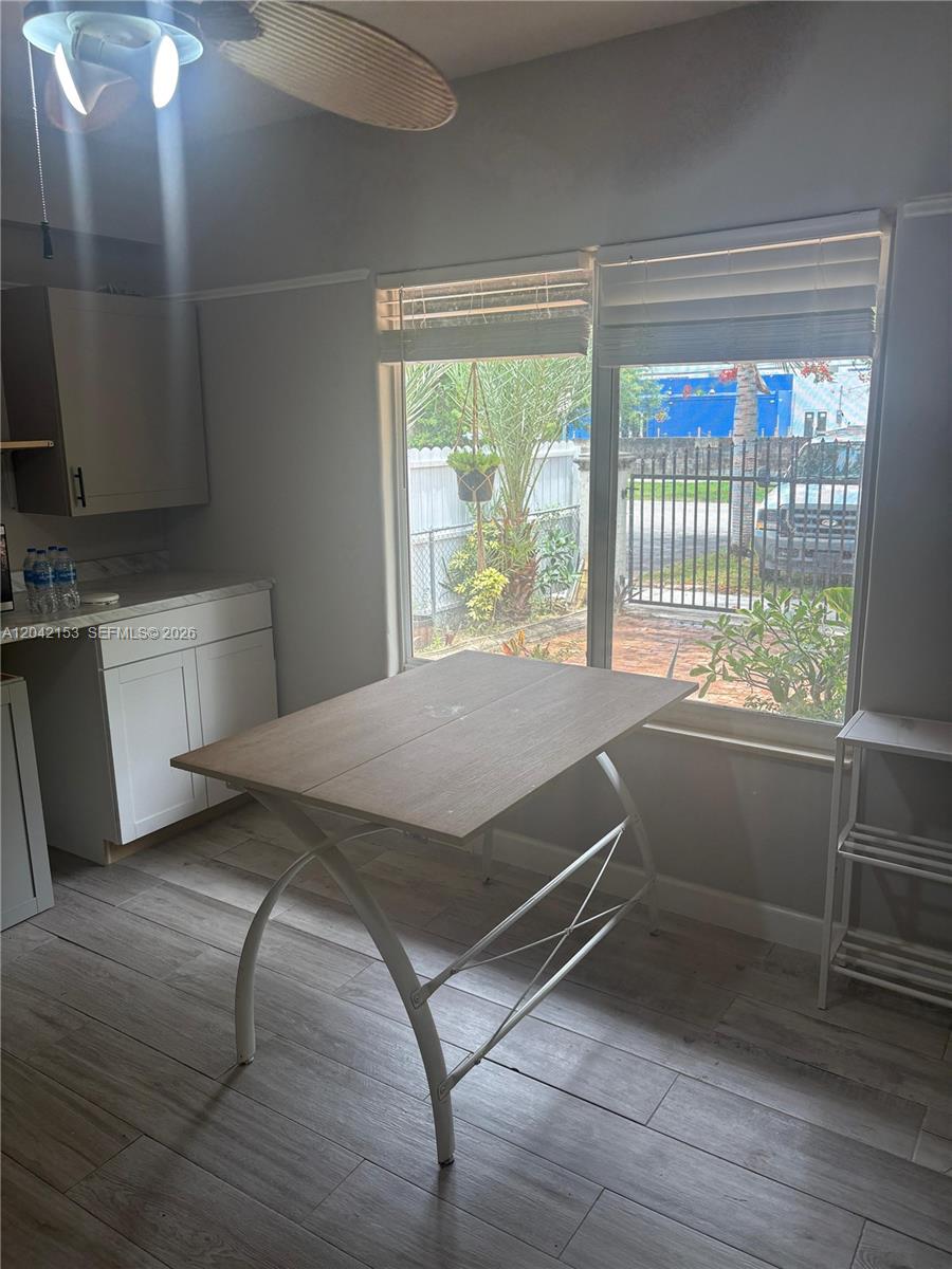 A kitchen area features white cabinets, a wood-top table, and windows overlooking a fenced yard — 6837 SW 39th Ter # 2, Miami FL 33155, MIAMI, FL