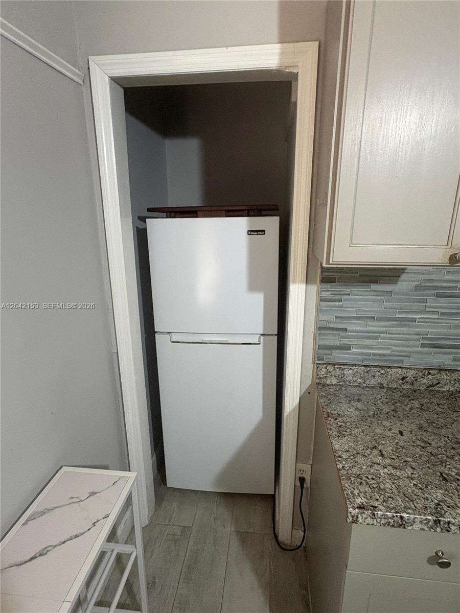 A white refrigerator sits inside a kitchen alcove next to granite countertops and cabinets — 6837 SW 39th Ter # 2, Miami FL 33155, MIAMI, FL