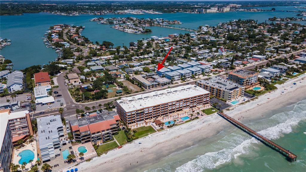 An aerial view shows a coastal neighborhood with a large beachfront condominium complex and pier — 16333 GULF BOULEVARD UNIT 113, REDINGTON BEACH, FL