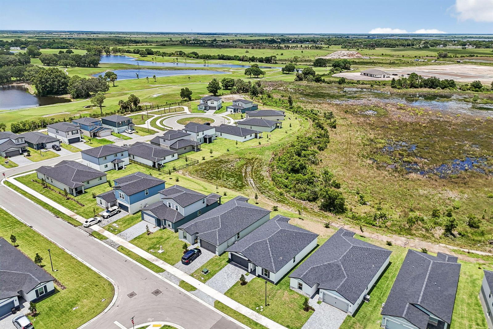 An aerial view shows a suburban neighborhood of single-family homes bordering a large grassy wetland — 15975 SW Vine Drive, FL 34956, FL