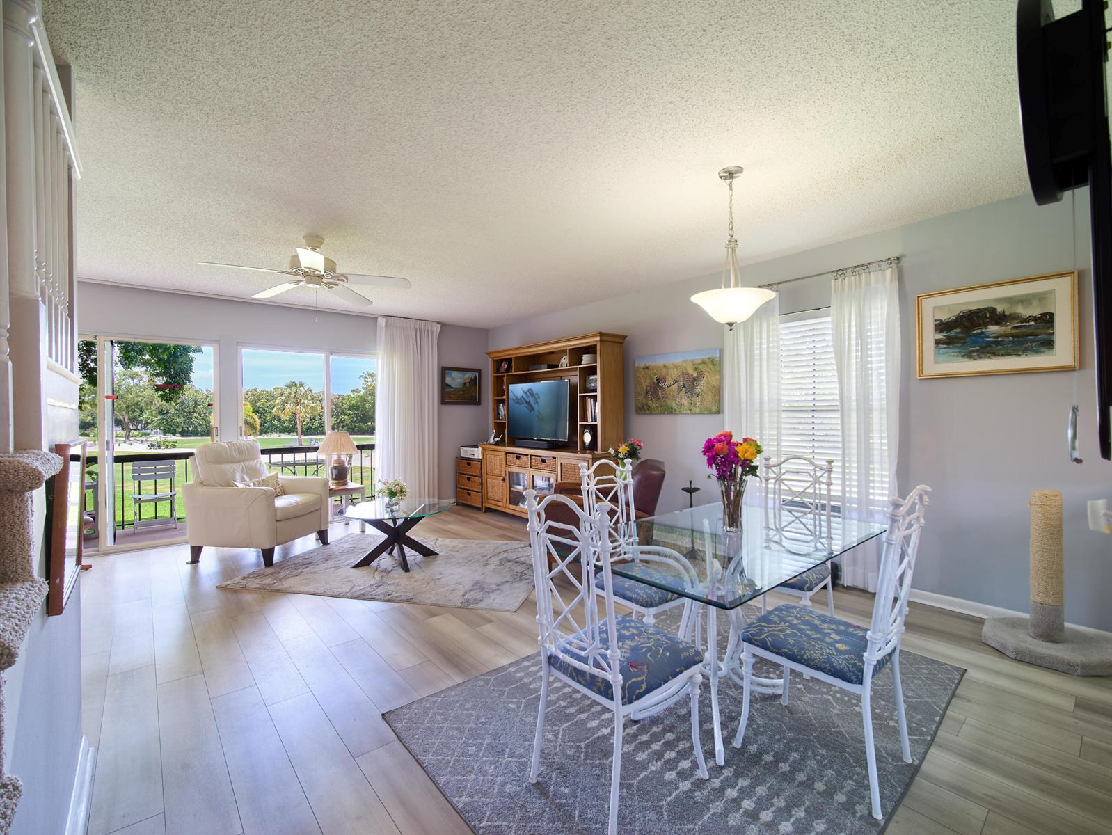 An open-concept living and dining area with light wood flooring, a glass table, and balcony — 18369 SE Wood Haven Lane, Jupiter FL 33469, JUPITER, FL