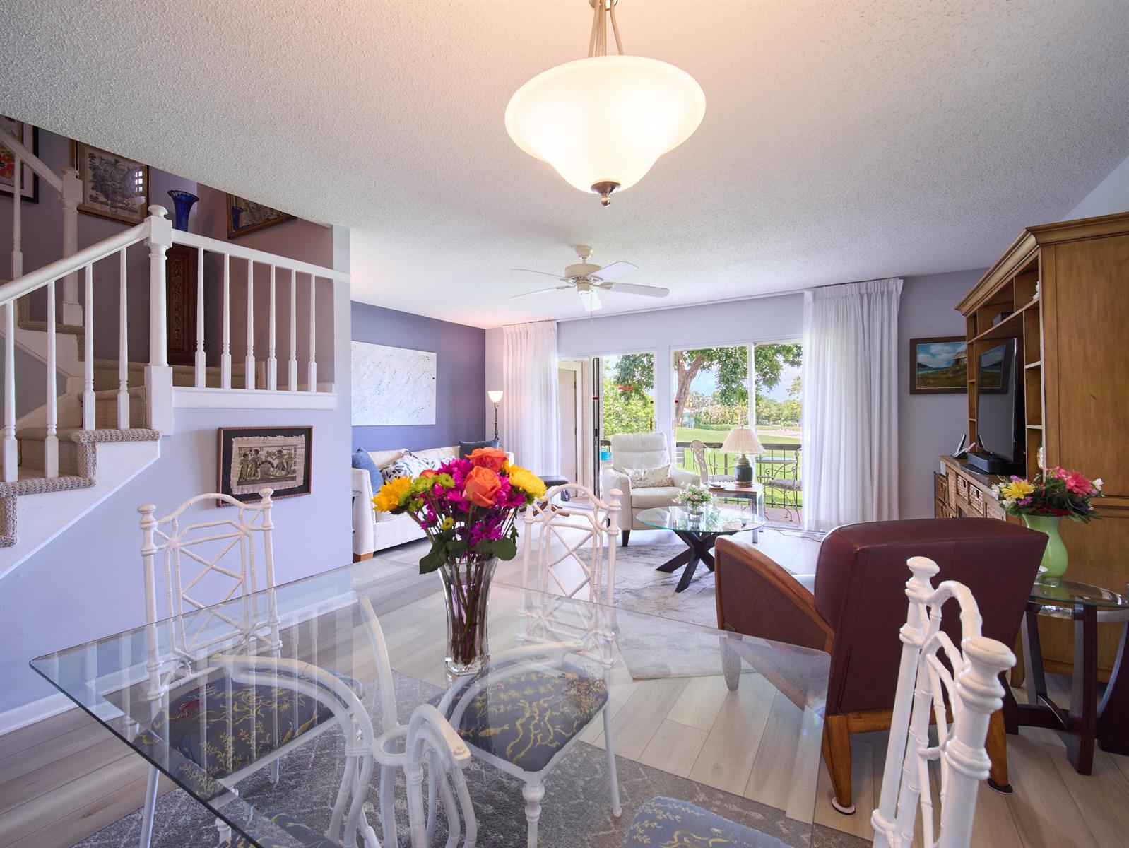 A dining area with a glass table overlooks a living room and a patio view — 18369 SE Wood Haven Lane, Jupiter FL 33469, JUPITER, FL