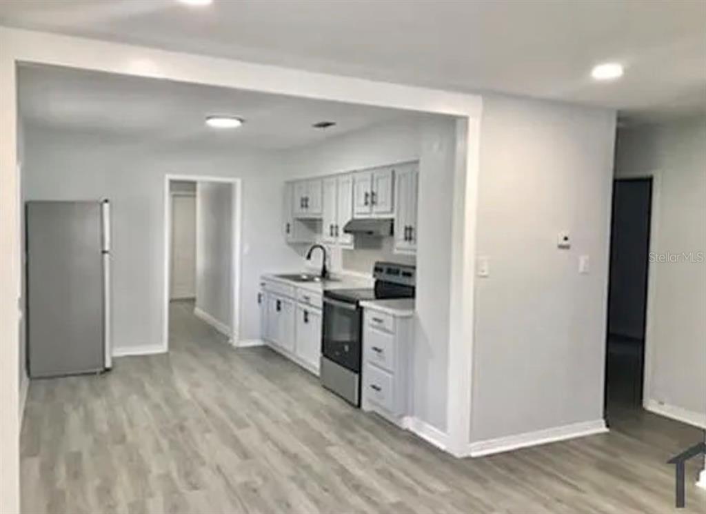 A kitchen with white cabinets, stainless steel appliances, and light wood-look flooring — 1706 W PALMETTO STREET, TAMPA, FL