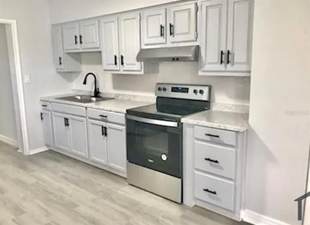 A kitchen features light gray cabinets, stainless steel appliances, and white countertops — 1706 W PALMETTO STREET, TAMPA, FL