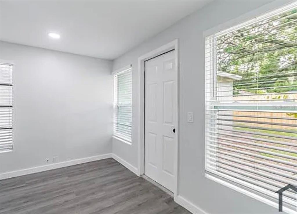A room with gray wood-look flooring, white walls, a white door, and two windows — 1706 W PALMETTO STREET, TAMPA, FL