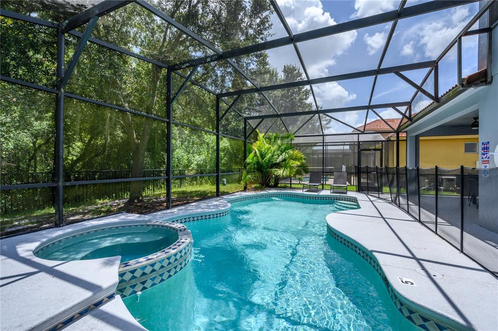 A screened-in swimming pool and spa with a concrete deck and surrounding metal fence — 1091 MARCELLO BOULEVARD, KISSIMMEE, FL