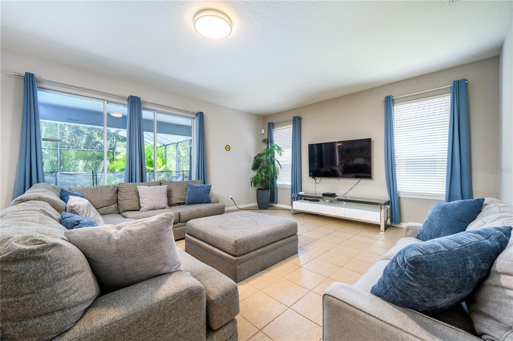 A living room features a sectional sofa, a large ottoman, and a wall-mounted television — 1091 MARCELLO BOULEVARD, KISSIMMEE, FL