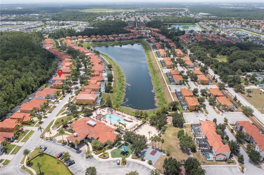 Aerial view of a residential community featuring a central lake, swimming pool, and townhomes — 1091 MARCELLO BOULEVARD, KISSIMMEE, FL