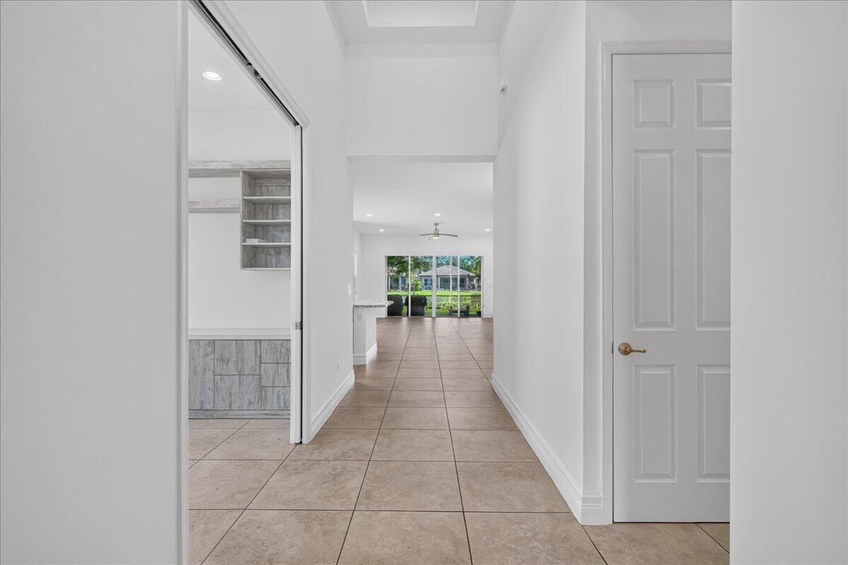 A hallway with tile flooring leads toward an open living area with a view outside — 8681 Cathedral Peak Court, Boynton Beach FL 33473, BOYNTON BEACH, FL