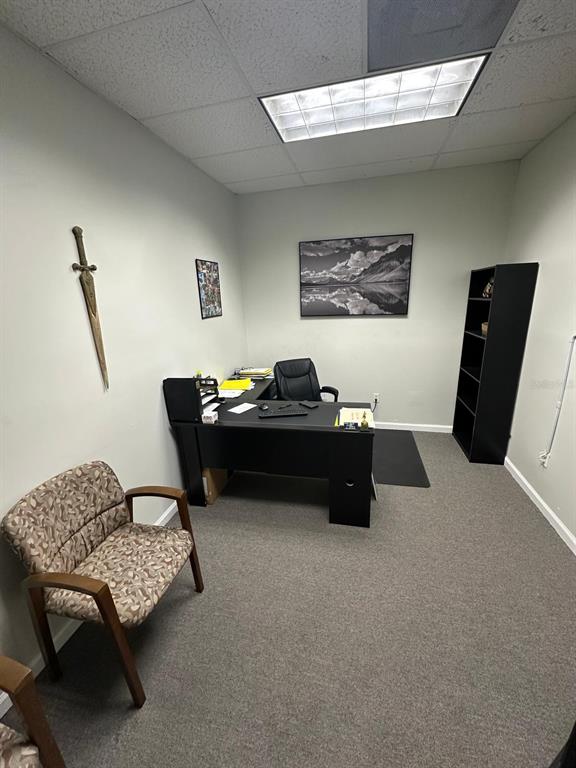 An office features a black desk, a patterned chair, a wall-mounted sword, and a bookshelf — 1340 CLEARMONT STREET NE UNIT 308, PALM BAY, FL