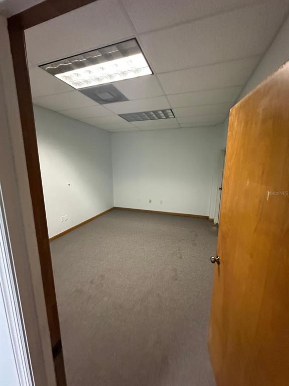An empty office room features light-colored walls, gray carpeting, and a drop ceiling with lights — 1340 CLEARMONT STREET NE UNIT 308, PALM BAY, FL