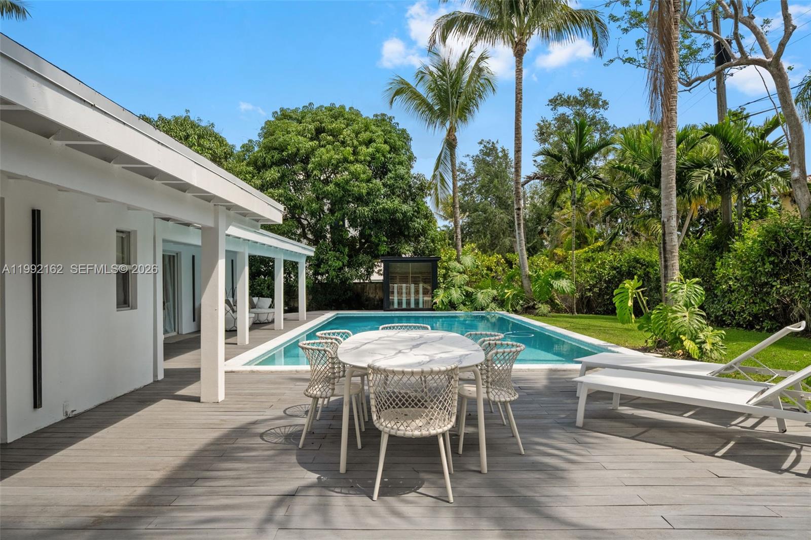 A patio with a dining set and lounge chairs overlooks a backyard swimming pool — 7531 SW 52nd Ct, Miami FL 33143, MIAMI, FL