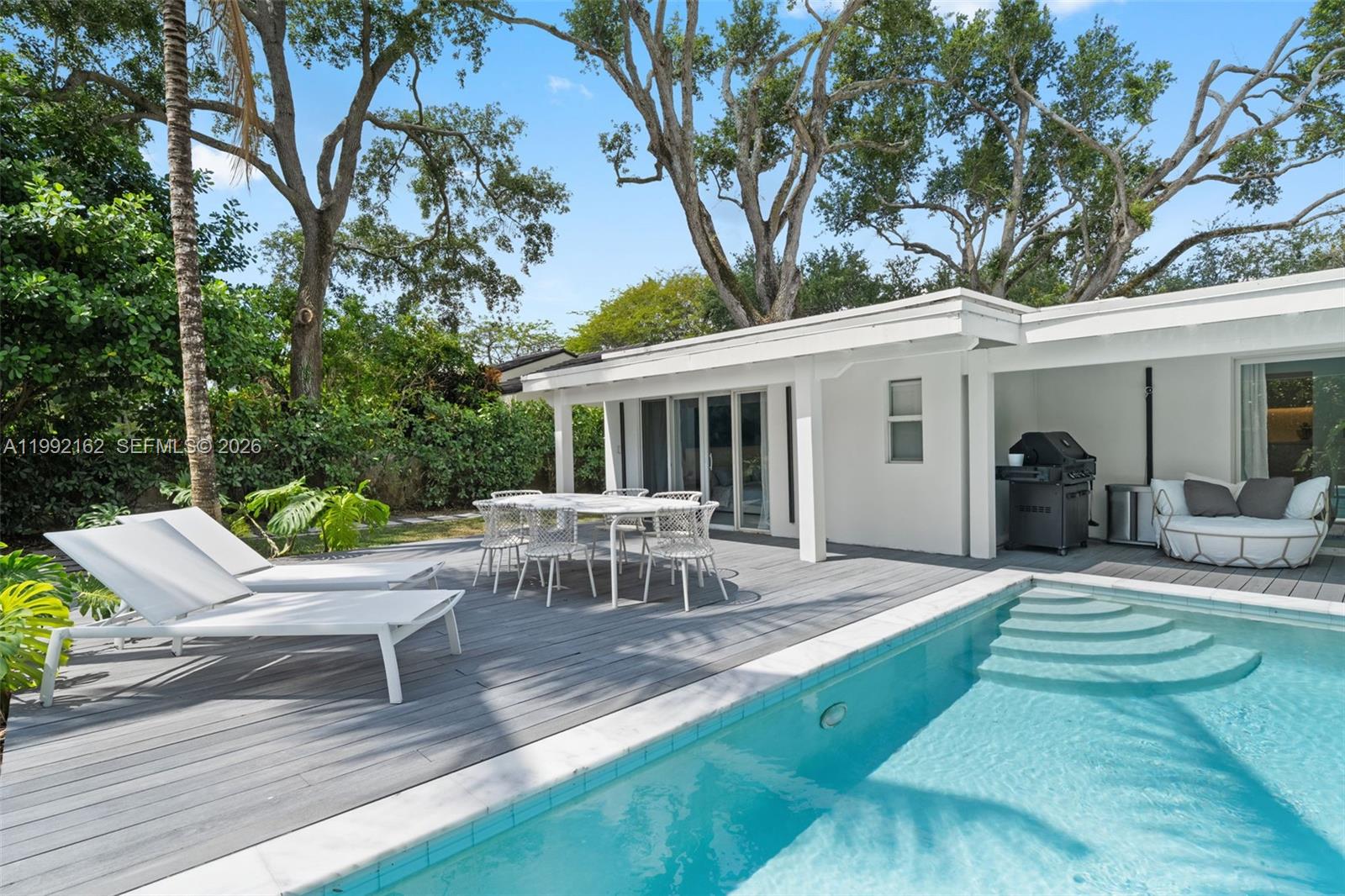 A white house with a pool, deck, outdoor dining set, and lounge chairs — 7531 SW 52nd Ct, Miami FL 33143, MIAMI, FL