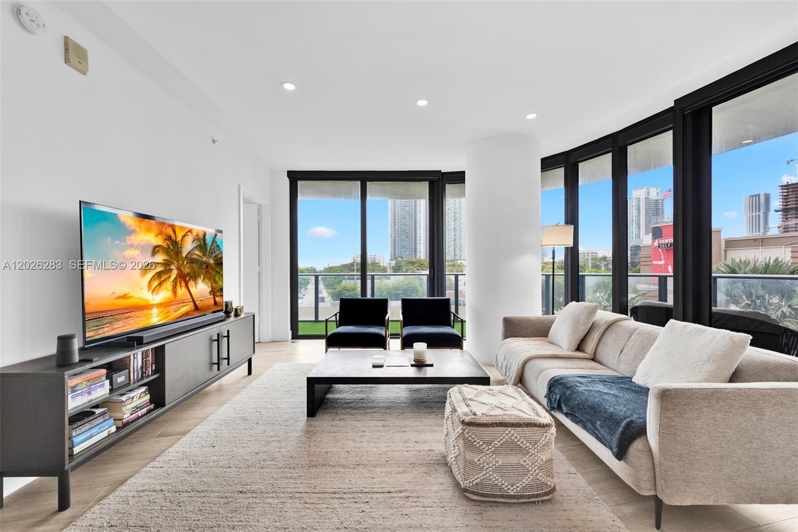 A modern living room features a television, sofa, coffee table, and floor-to-ceiling windows — 121 NE 34th St # L304, Miami FL 33137, MIAMI, FL