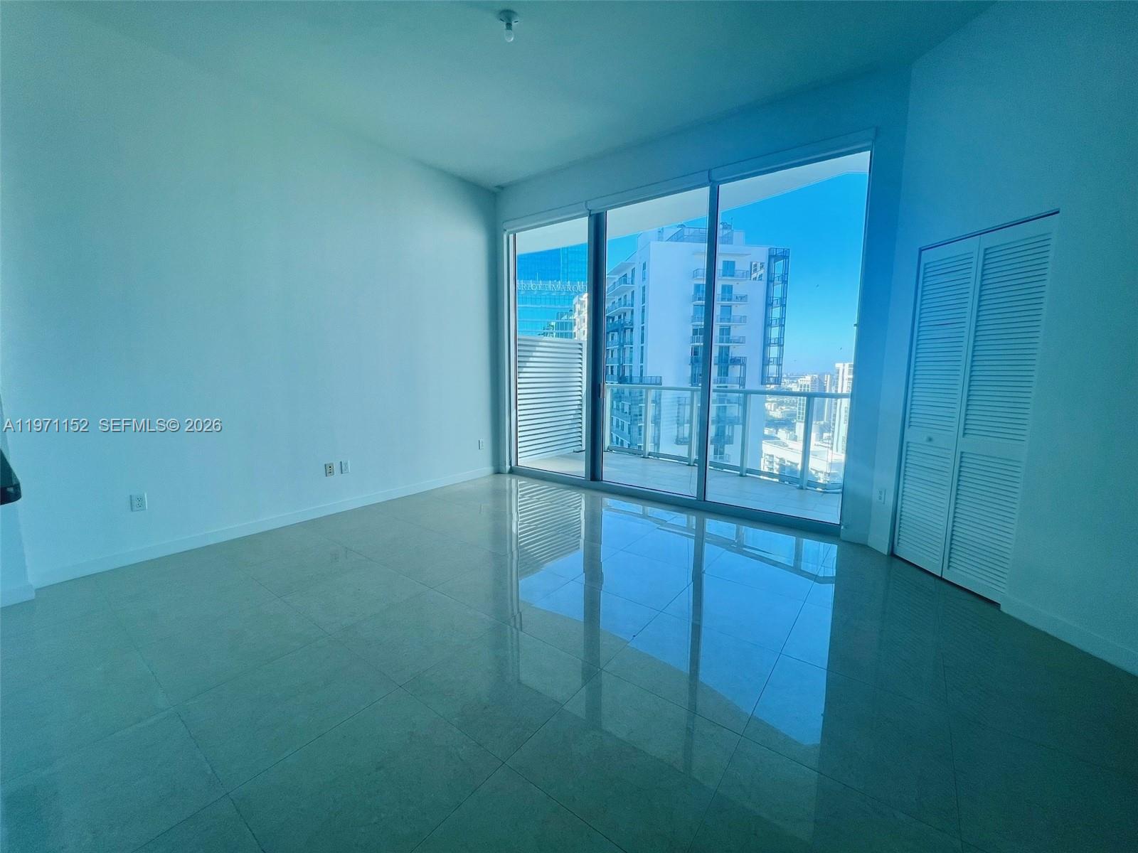 An empty room features light-colored tile floors, white walls, and floor-to-ceiling windows overlooking a city — 300 S Biscayne Blvd # 3907, Miami FL 33131, MIAMI, FL