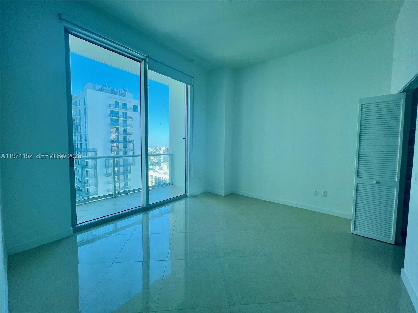 An empty room with light-colored tile floors, white walls, and a large sliding glass door — 300 S Biscayne Blvd # 3907, Miami FL 33131, MIAMI, FL