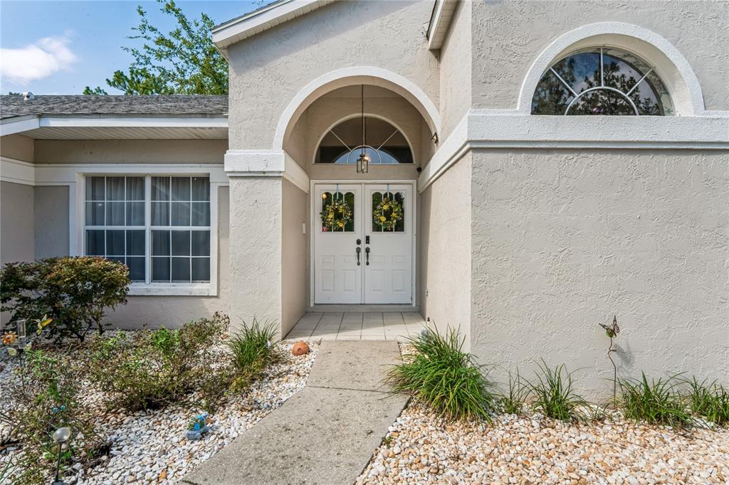 The exterior of a house features a double front door under an arched entryway — 4 SPRUCE PINE COURT N, HOMOSASSA, FL