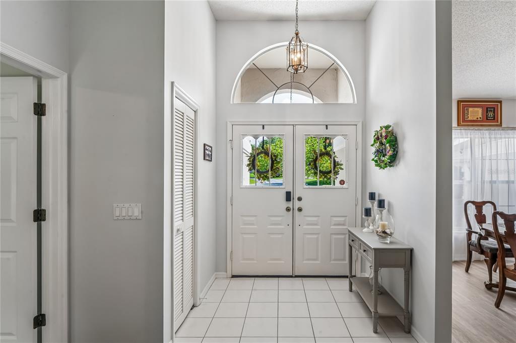 A bright entryway features white tile flooring, double front doors, and a high arched window — 4 SPRUCE PINE COURT N, HOMOSASSA, FL
