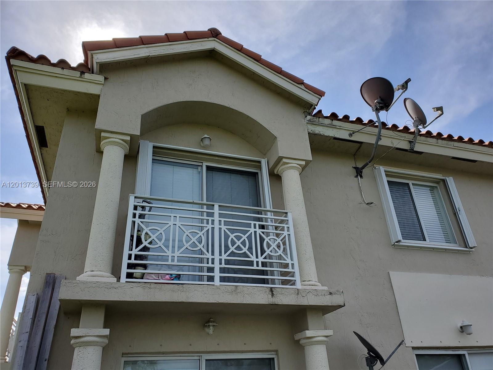 A two-story stucco building features a balcony with a white geometric railing and satellite dishes — 8804 NW 109th Pl # 402, Doral FL 33178, DORAL, FL