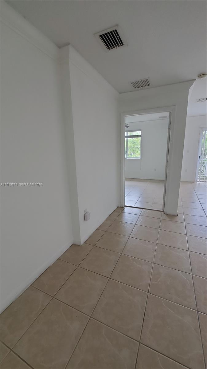 A hallway with beige tile flooring leads to an open doorway revealing a bright room — 8804 NW 109th Pl # 402, Doral FL 33178, DORAL, FL