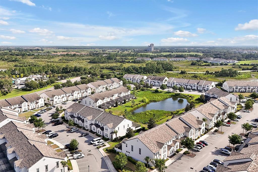An aerial view shows multiple rows of townhomes surrounding a central pond and parking areas — 297 CAPTIVA DRIVE, DAVENPORT, FL