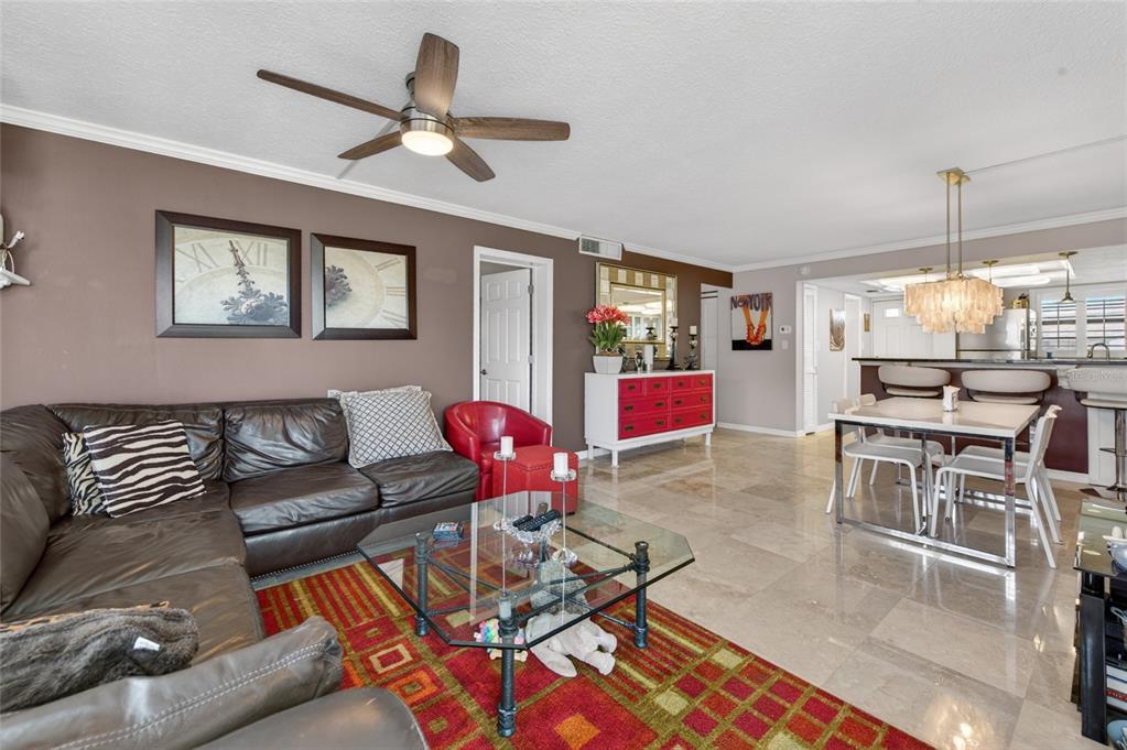 A living room with a brown leather sectional, red accent chair, and dining area — 4811 SAXON DRIVE UNIT A-203, NEW SMYRNA BEACH, FL