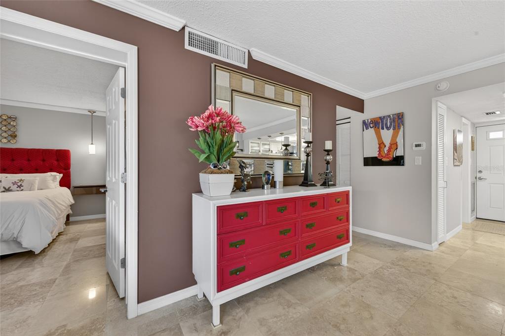 A white dresser with red drawers sits against a brown wall in a tiled hallway — 4811 SAXON DRIVE UNIT A-203, NEW SMYRNA BEACH, FL