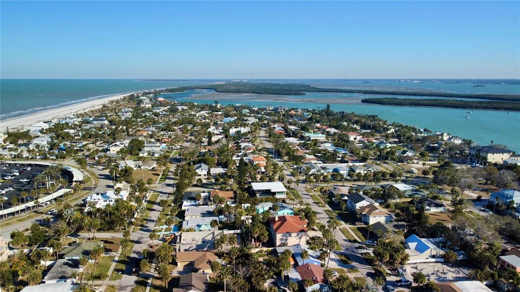 An aerial view shows a coastal neighborhood with houses, palm trees, and nearby water — 843 BRUCE AVENUE, CLEARWATER BEACH, FL