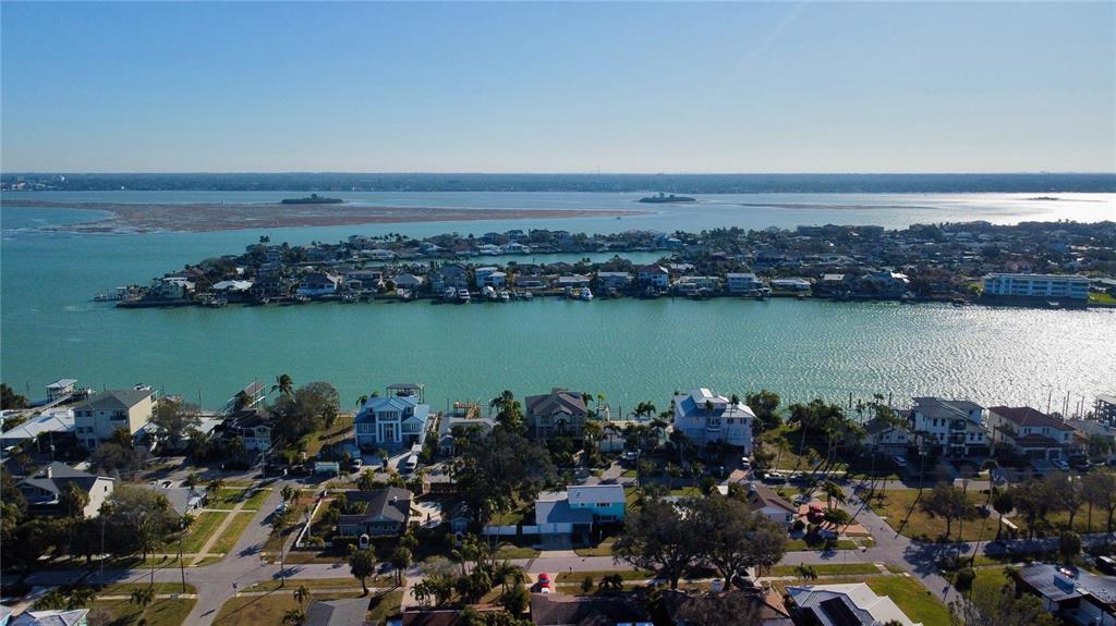 An aerial view shows waterfront houses along a canal with a bay in the background — 843 BRUCE AVENUE, CLEARWATER BEACH, FL