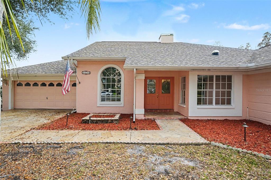 A single-story house with pink stucco walls, a stone walkway, and a two-car garage — 4814 TANNERY AVENUE, TAMPA, FL