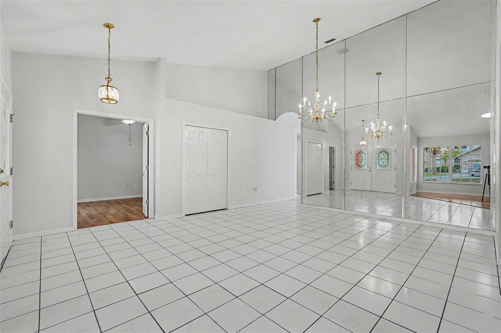A bright room features white tile flooring, a mirrored wall, and two hanging chandeliers — 4814 TANNERY AVENUE, TAMPA, FL