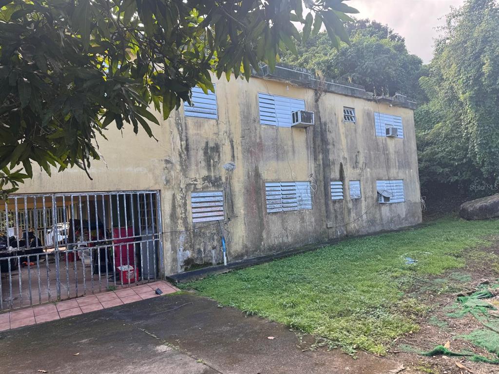 A two-story concrete building with louvered windows, window air conditioning units, and a gated carport — 185 KM 6.1 CAMPO RICO ROAD, CANOVANAS, PR
