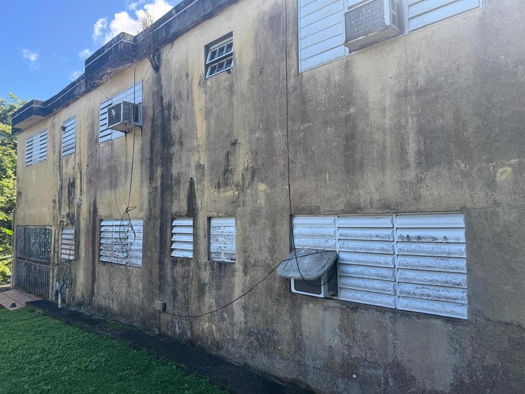 The exterior of a weathered, two-story concrete building features multiple louvered windows and air conditioning units — 185 KM 6.1 CAMPO RICO ROAD, CANOVANAS, PR